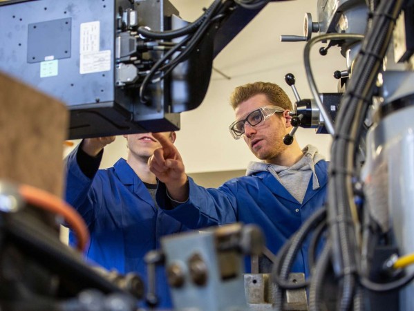 two people in boiler suits looking at a workshop screen