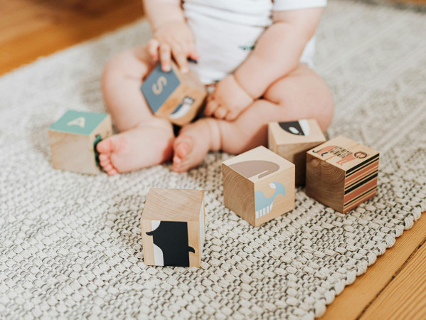 baby sat on the floor playing with blocks