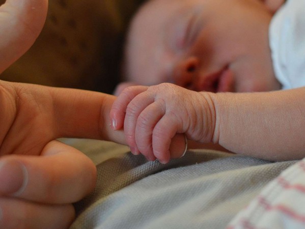 newborn baby holding an adult finger