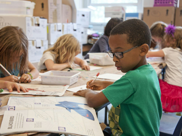 boy in a green shirt does some school work in a classroom